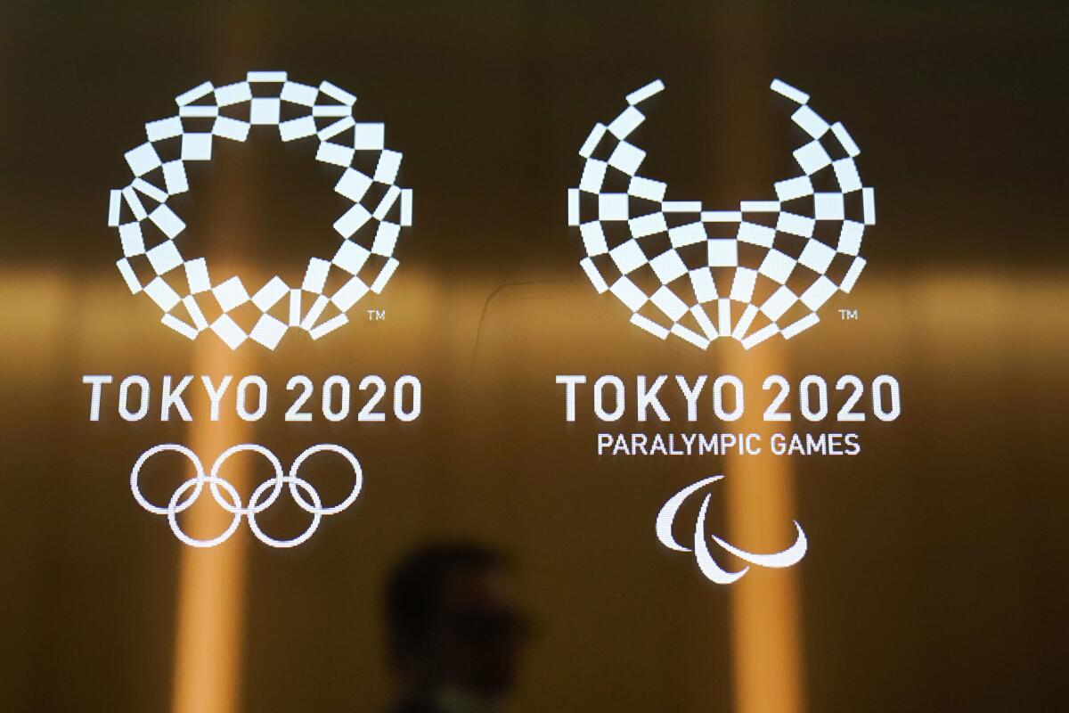 ARCHIVO - En esta foto del 11 de junio de 2019, un hombre pasa frente a los logos de los Juegos Olímpicos y Parlímpicos de Tokio 2020. (AP Foto/Jae C. Hong, archivo) ** Usable by HOY, ELSENT and SD Only **