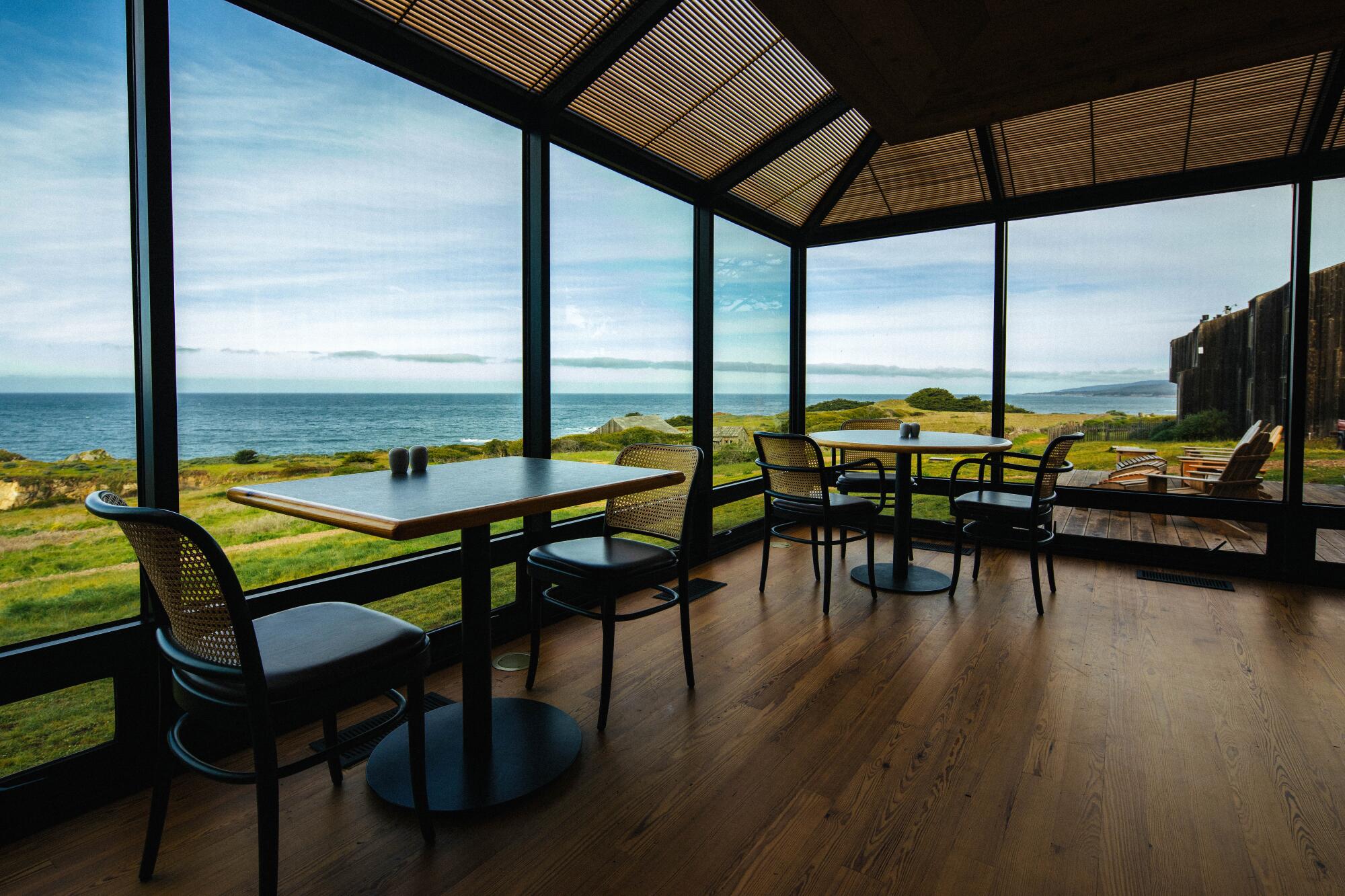 A lounge/dining area with large windows that look out onto the coast.