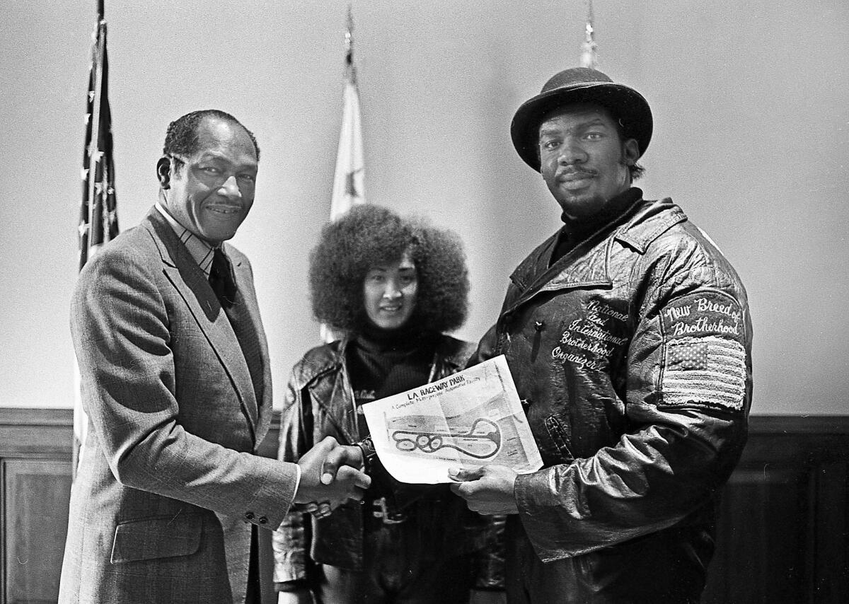 Then-L.A. Mayor Tom Bradley, left, shakes hands with Big Willie after making a deal to open Brotherhood Raceway Park. At center is Big Willie’s wife, Tomiko, who was also a street racer. (Howard Koby)