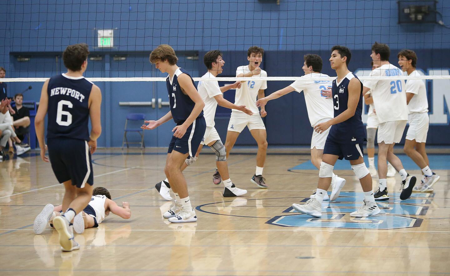 Corona del Mar, in white, celebrate winning a tough point during second round of the Battle of the Bay boys' volleyball match against Newport Harbor in Surf League play on Wednesday.