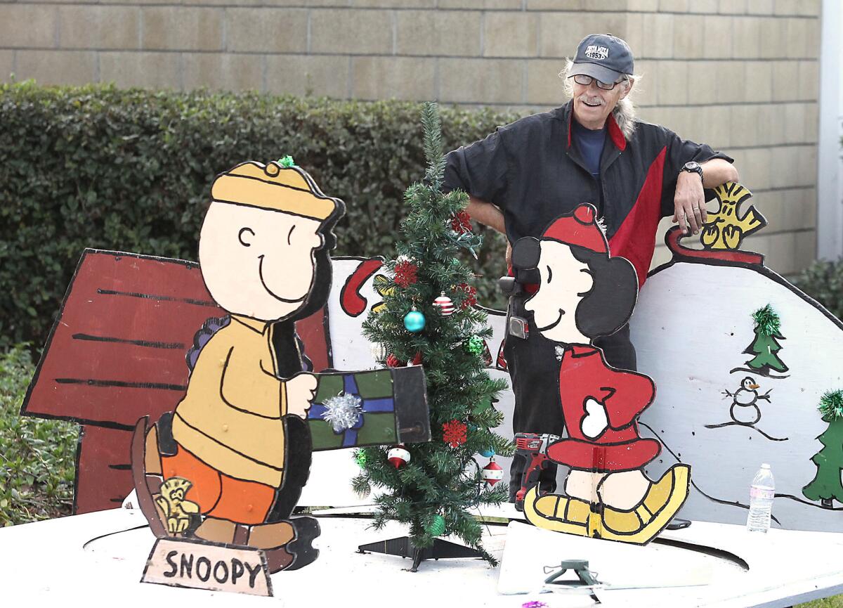 Volunteer Steve Klaustermeier overlooks the completion of the Charlie Brown and Lucy skating rink as he and others prepare the Snoopy House Christmas in front of Costa Mesa city hall on Thursday.