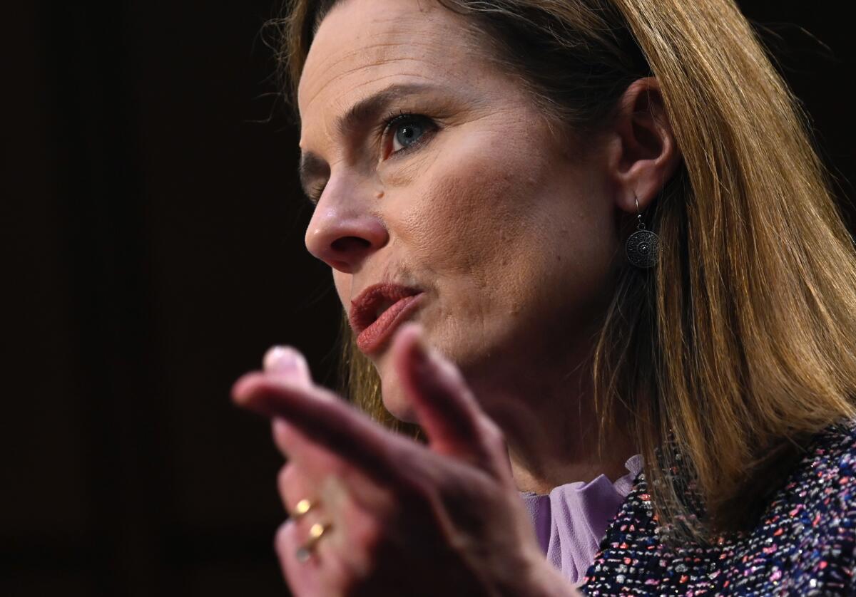 Amy Coney Barrett gestures with one hand as she testifies at her confirmation hearing.