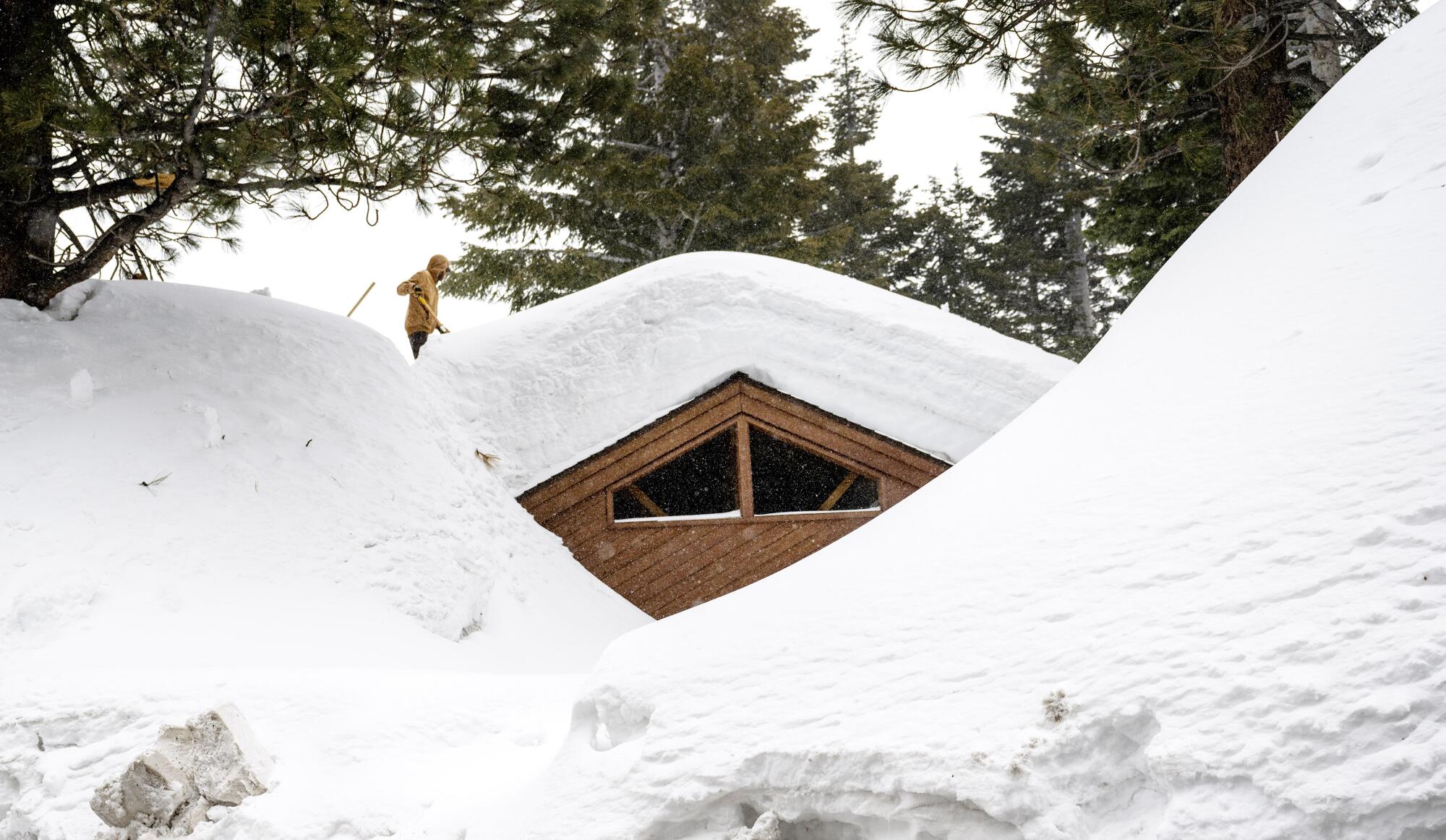 A resident clears snow off the roof of his house in Mammoth Lakes.