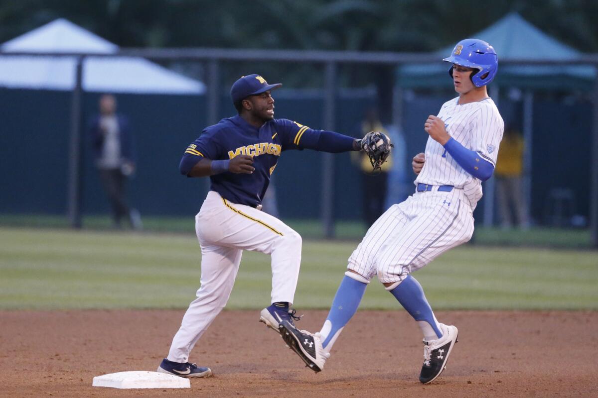 Michigan's Ako Thomas (4) tags out UCLA's Michael Toglia (7) on an attempted steal of second base during the NCAA tournament super regional game on Friday at UCLA.