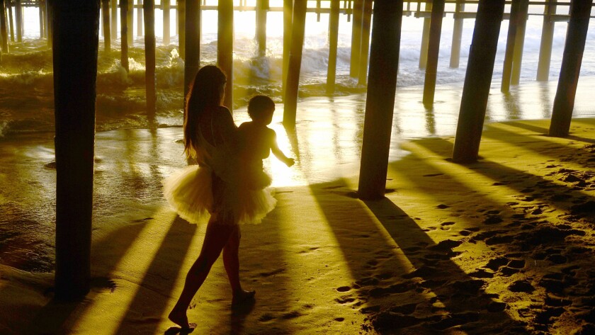 A woman walks under the Santa Monica pier at sunset in Santa Monica. Triple-digit temperatures are expected to hit the region by the end of the week.