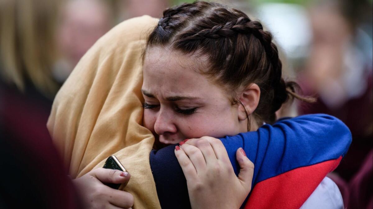 Students comfort each other during a vigil in Christchurch on Monday. The 50 killed in the attack on two mosques included students.