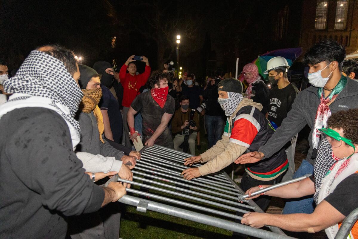 Protesters hold two sides of a metal barricade