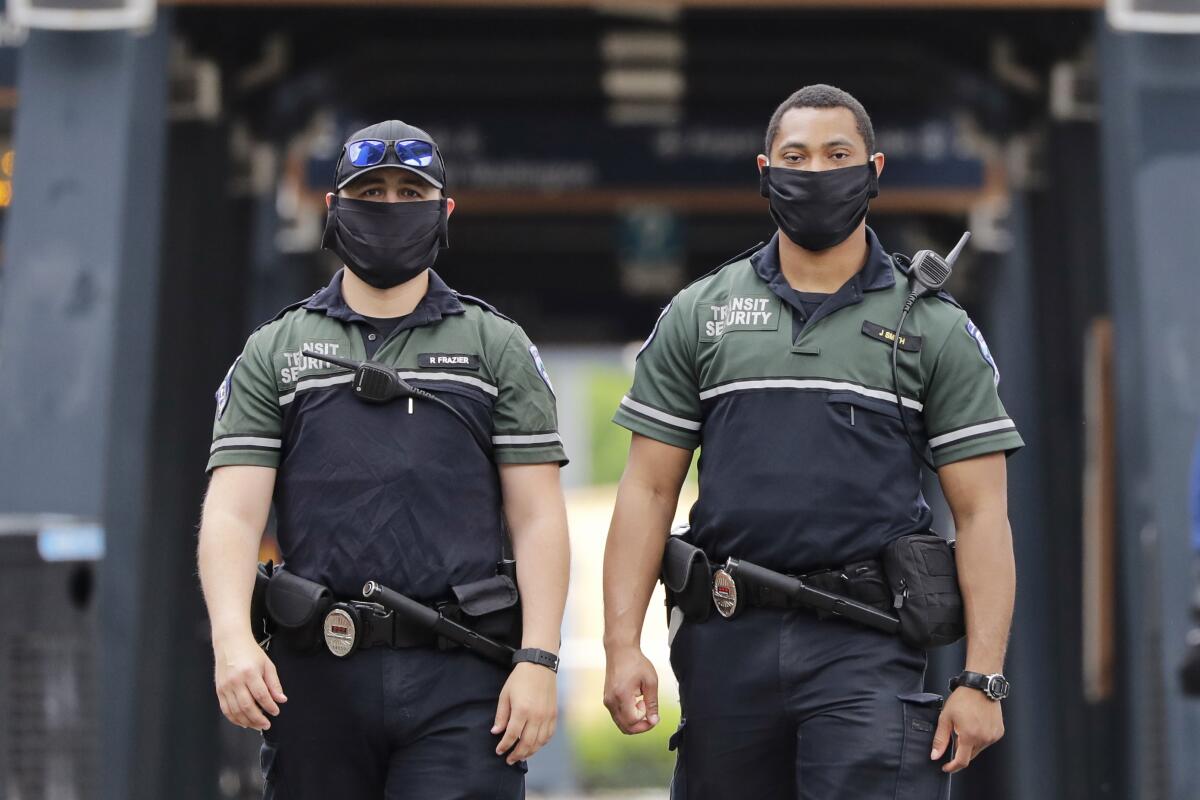 Dos elementos de seguridad del metro del condado King portan mascarillas para protegerse del coronavirus el lunes 11 de mayo de 2020, en Seattle. (AP Foto/Elaine Thompson)