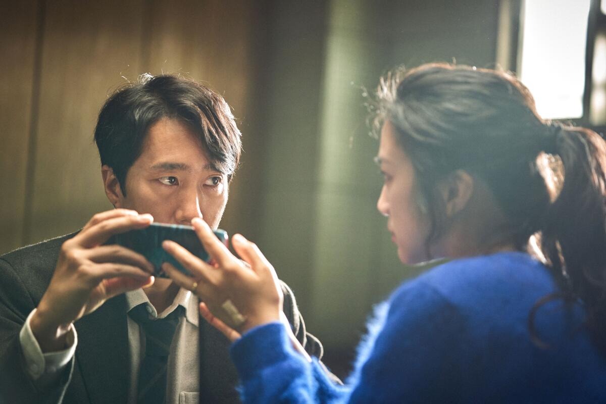 A man, left, sips from a bowl while another woman gestures 