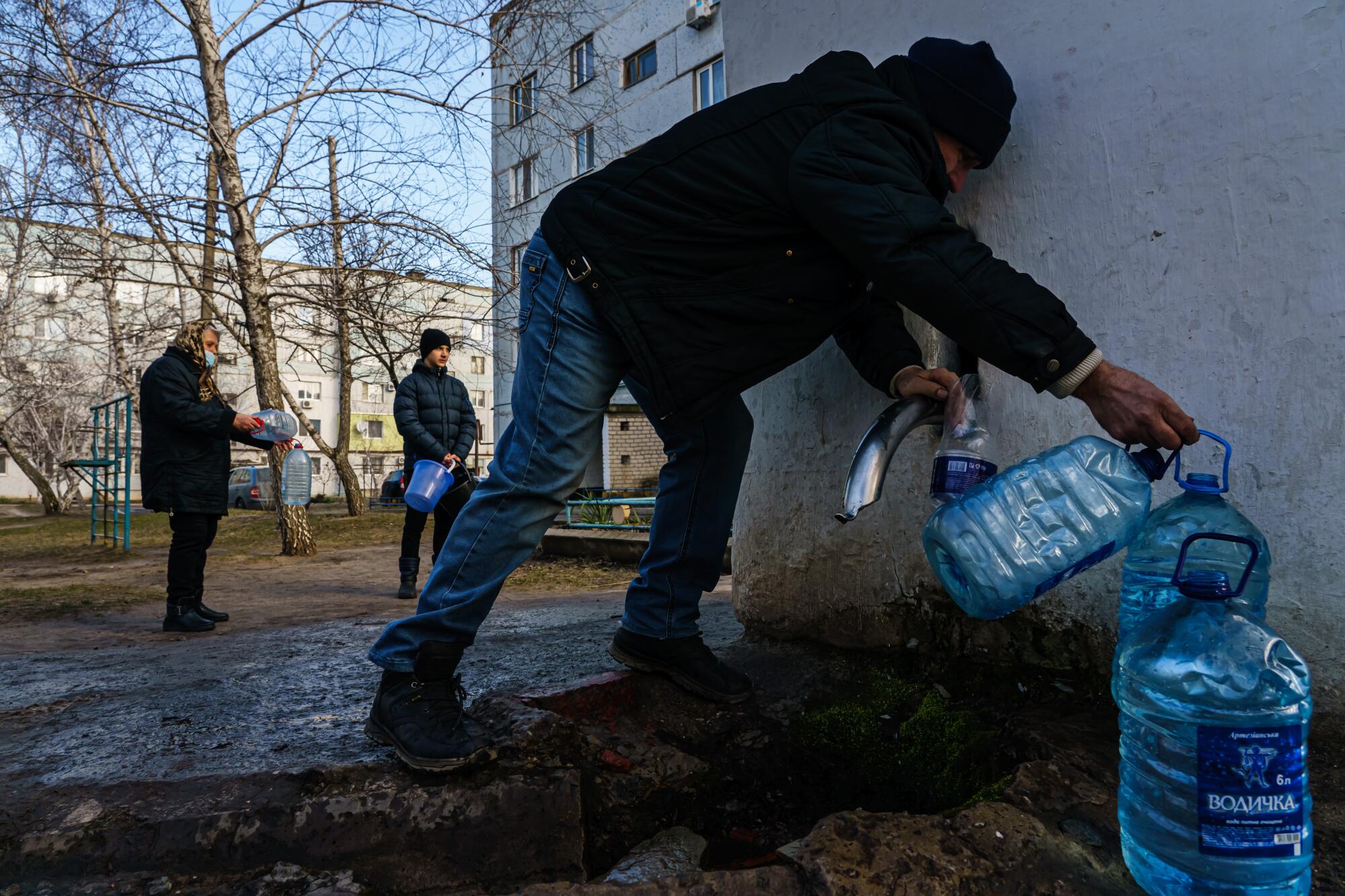 People whose water service at home has been disrupted line up to get water at a central pumping station in Schastia, Ukraine