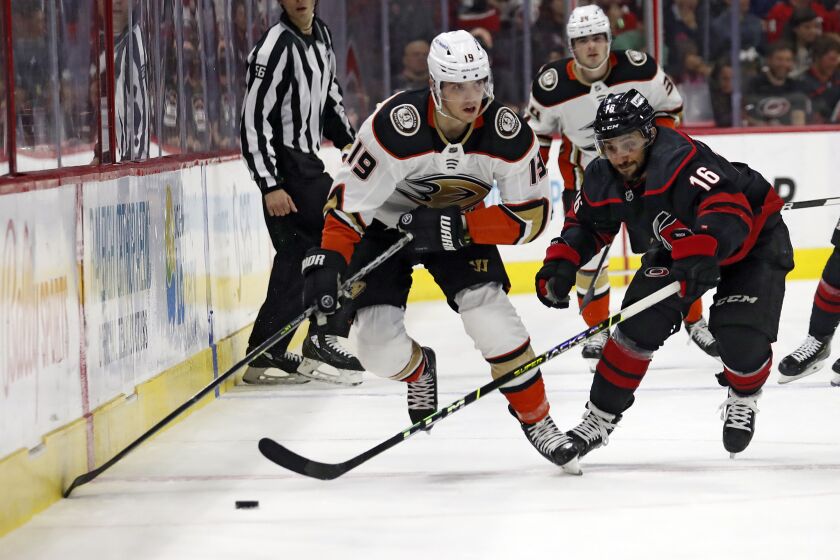 Anaheim Ducks' Troy Terry (19) attempts to move the puck past Carolina Hurricanes' Vincent Trocheck.