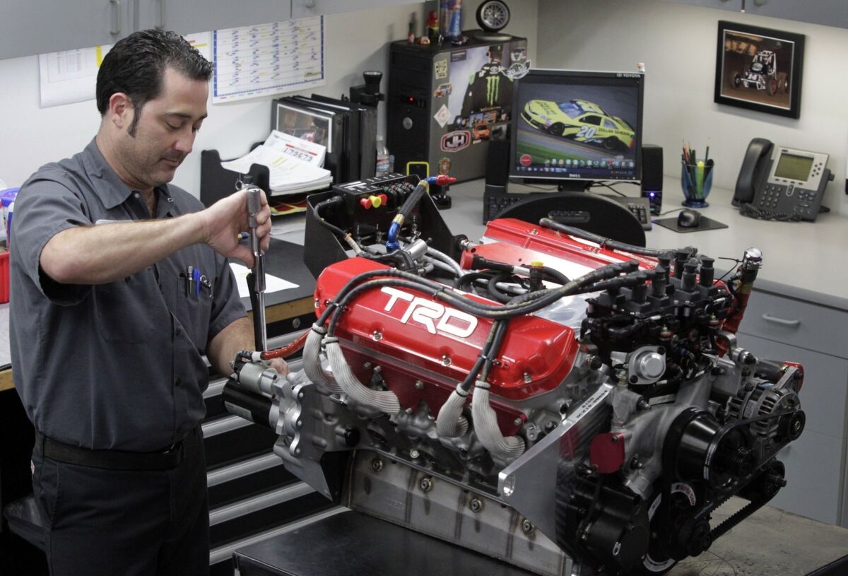 Toyota Racing Development technician J.J. Ercse tightens a bolt with a torque wrench while doing final preparation work on an engine that will be used in a NASCAR race.