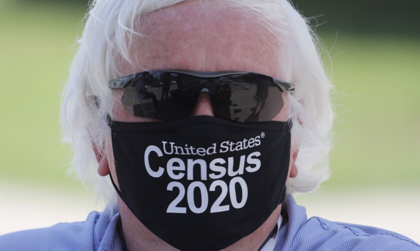 A census worker wears a mask with the words "U.S. Census 2020." 