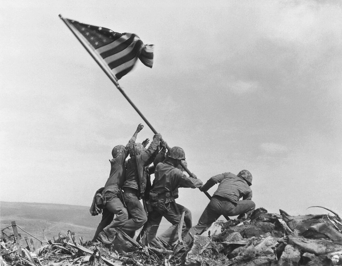 Marines raise an American flag atop Mount Suribachi, Iwo Jima, in 1945.