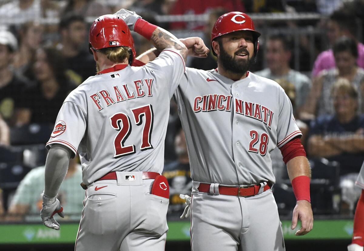 Cincinnati Reds' Jake Fraley is greeted by teammate Austin Romine (28) after his two-run home run off Pittsburgh Pirates pitcher Tyler Beede scored them both during the fourth inning of a baseball game, Saturday, Aug. 20, 2022, in Pittsburgh. (AP Photo/Philip G. Pavely)