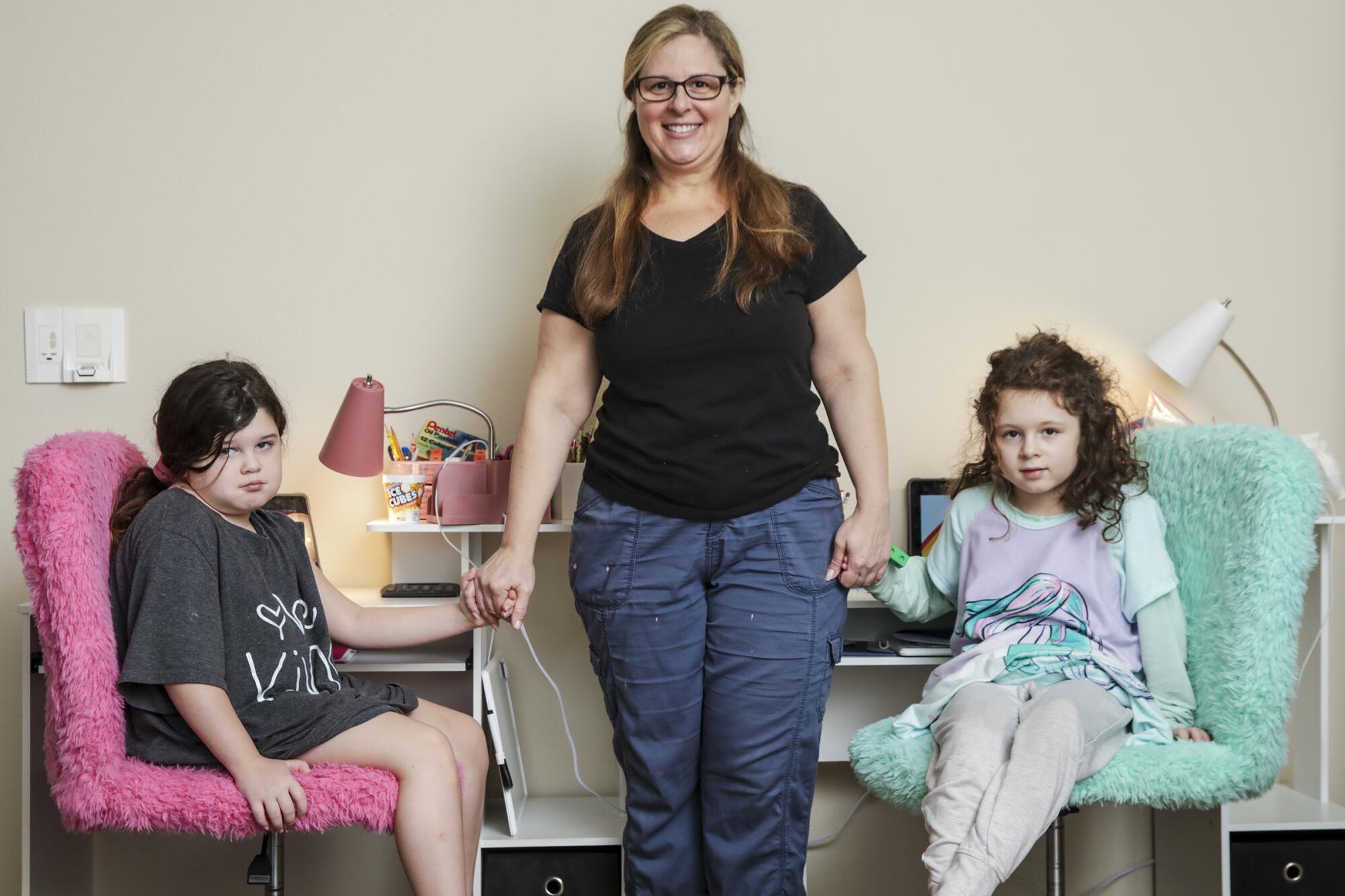 Alison Goldberg, 43, stands for a portrait with her 7-year-old twins Savannah Singer and Madelynn Singer at home.