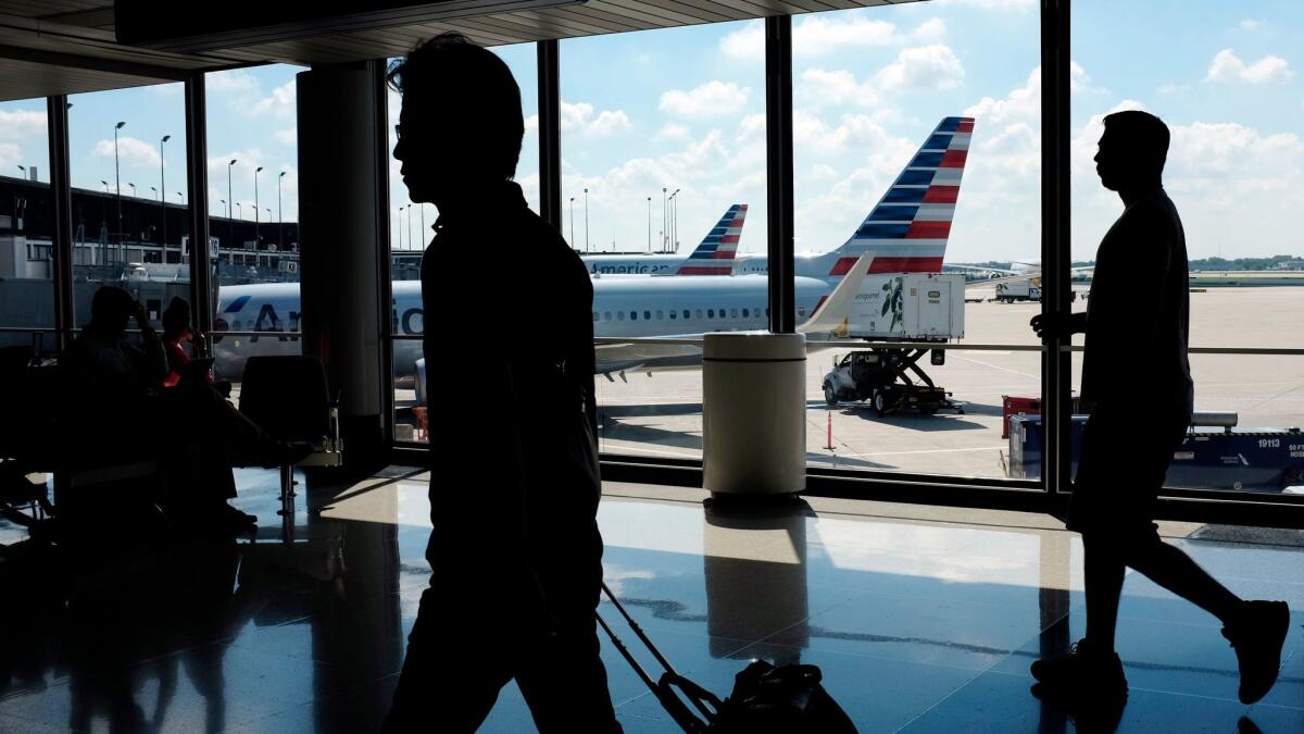 Passengers walk to their gates through the terminal as American Airlines planes wait to depart at Chicago's O'Hare International Airport.