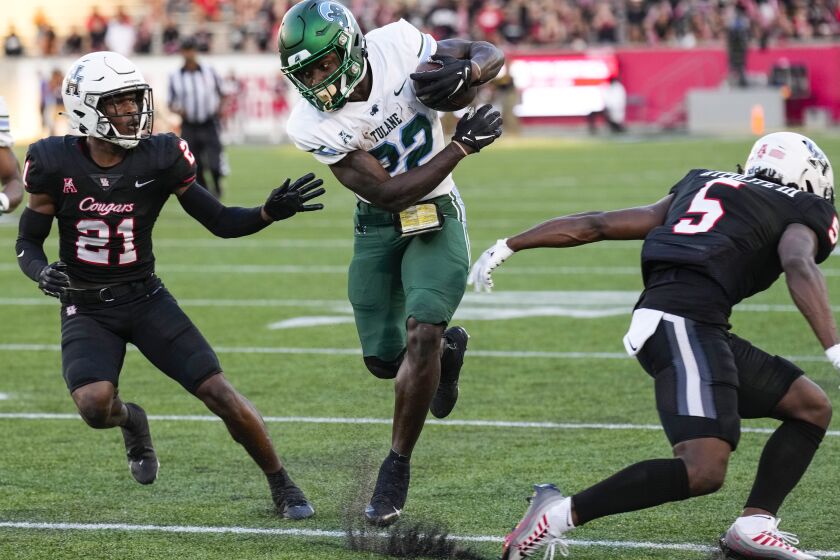 Tulane running back Tyjae Spears (22) cuts back between Houston defensive backs Abdul-Lateef Audu (21) and Hasaan Hypolite (5) on a reception for a first down during the second quarter of an NCAA college football game Friday, Sept. 30, 2022, in Houston. (Brett Coomer/Houston Chronicle via AP)