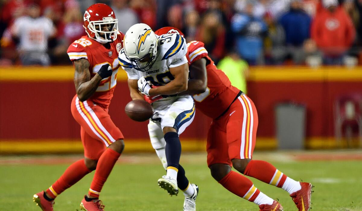 Kansas City Chiefs cornerback Marcus Peters, left, and inside linebacker Reggie Ragland strip the ball from Chargers running back Austin Ekeler during Saturday's game.