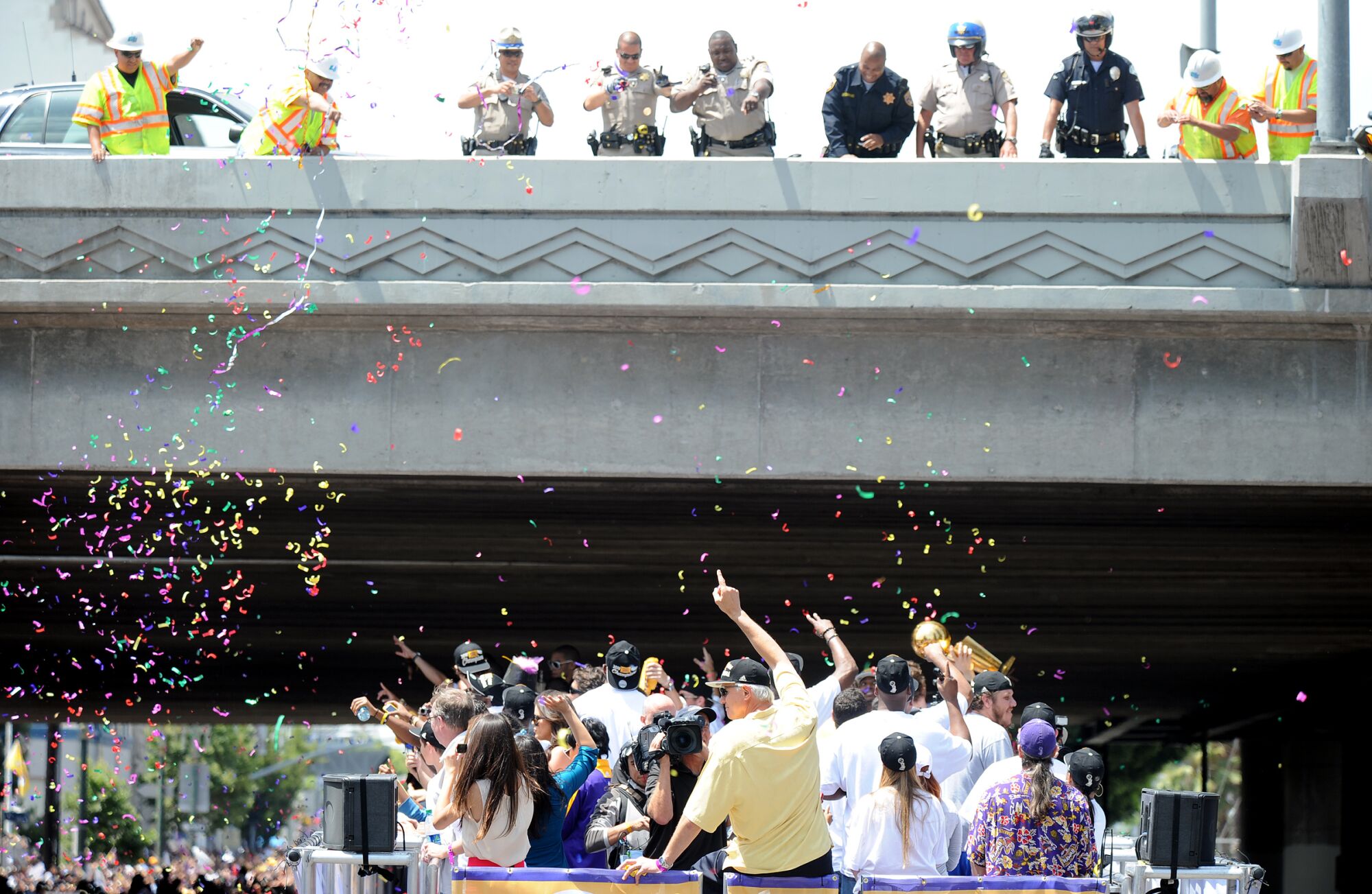 A crew of law enforcement officers watch the Lakers championship bus roll underneath the 10 Freeway.