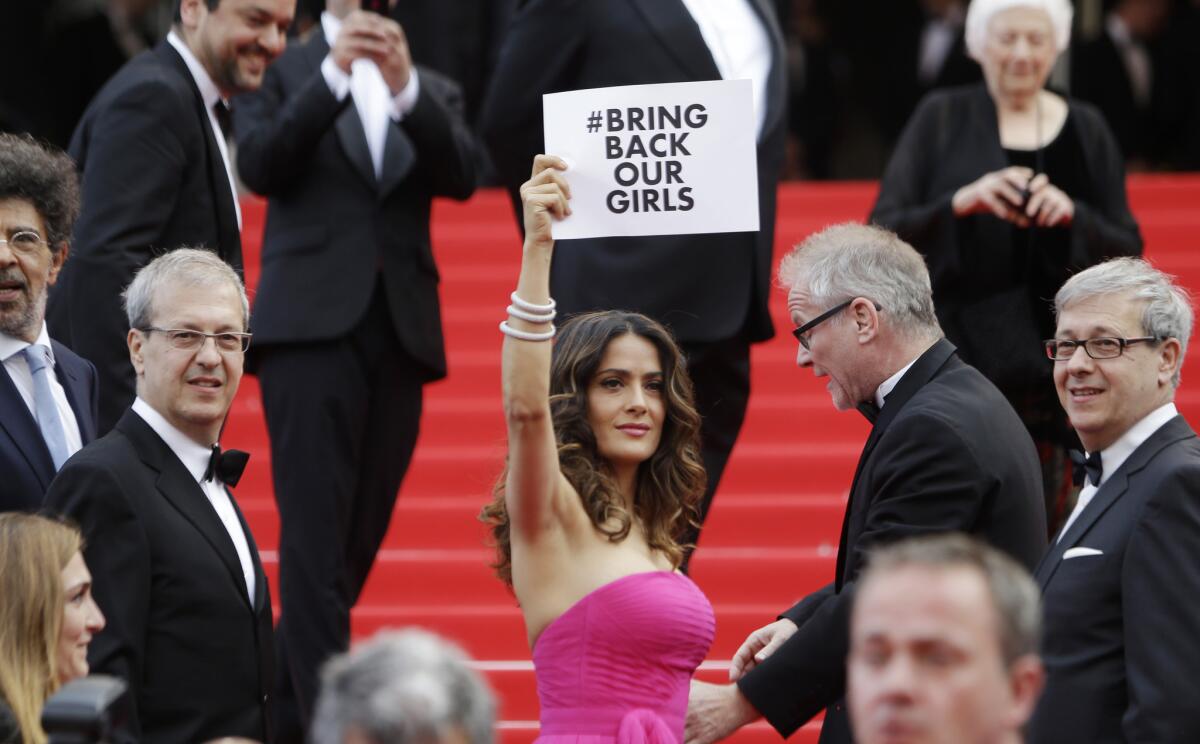 Actress Salma Hayek holds up a sign reading "#Bring back our girls" as she arrives for the screening of "Saint-Laurent" at the Cannes film festival.