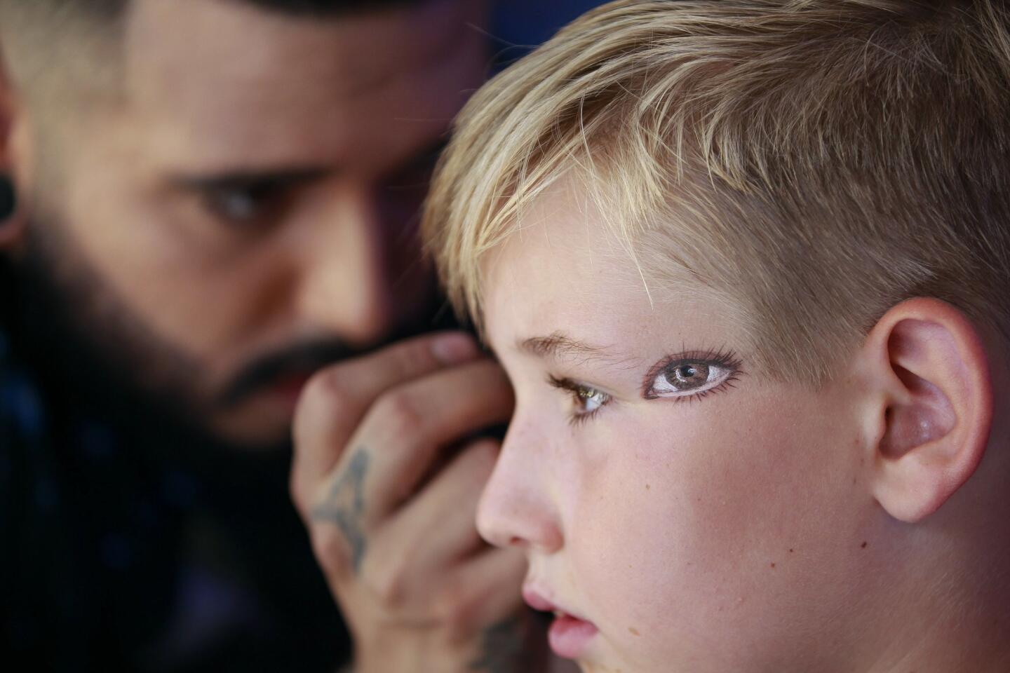 Lawson Cahill, 6, from San Diego, gets the second of two eyes painted on each temple by makeup artist Will Carrillo at the Mac Cosmetics booth outside of the San Diego Convention Center.