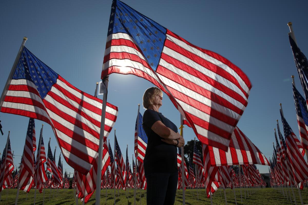 A woman stands amid an installation of fluttering flags on the grounds of Sierra Vista Middle School.