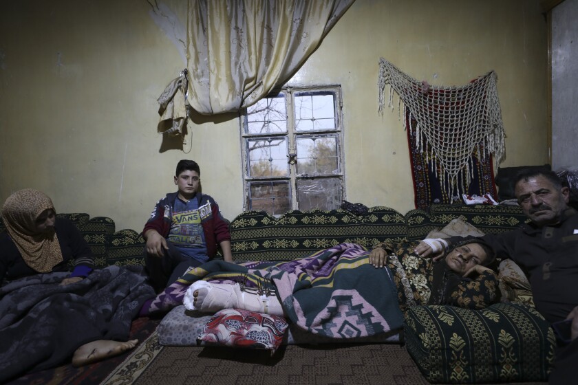 Ahmad Qassim, a la derecha, acompaña a su esposa luego de que ambos resultaron heridos en un bombardeo de Estados Unidos, el lunes 6 de diciembre de 2021, en su vivienda de la localidad de Al Rami, provincia de Idlib, Siria. (AP Foto/Ghaith Alsayed)