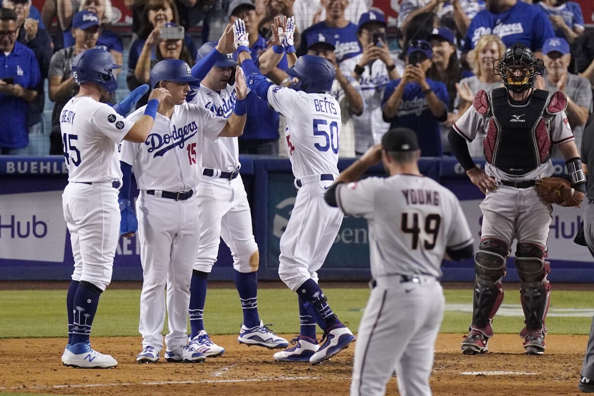 The Dodgers' Mookie Betts (50) is congratulated by teammates after hitting a seventh-inning grand slam July 10, 2021.