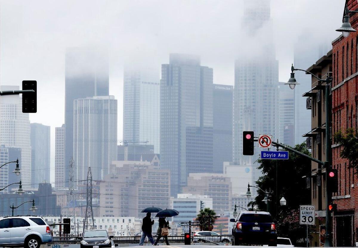 Pedestrians cross First Street in Boyle Heights under wet weather Wednesday.