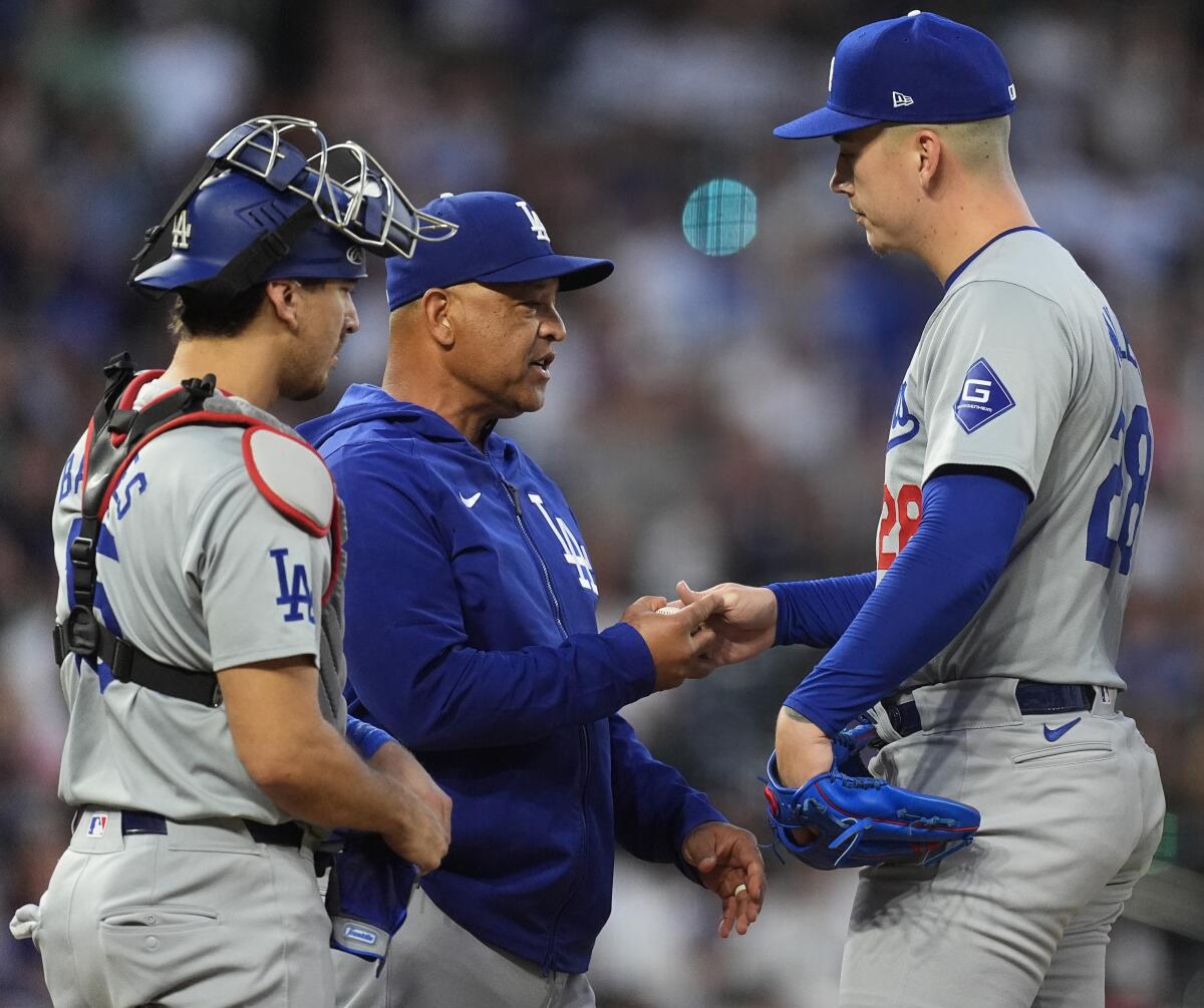 Manager Dave Roberts, center, takes the ball from right-hander Bobby Miller with catcher Austin Barnes at left.