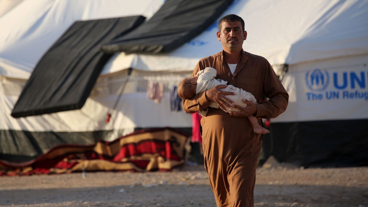 A man carries a baby at a refugee camp in Syria's Hasakeh province for Iraqi families who fled fighting in the Mosul area on Oct. 17, 2016.