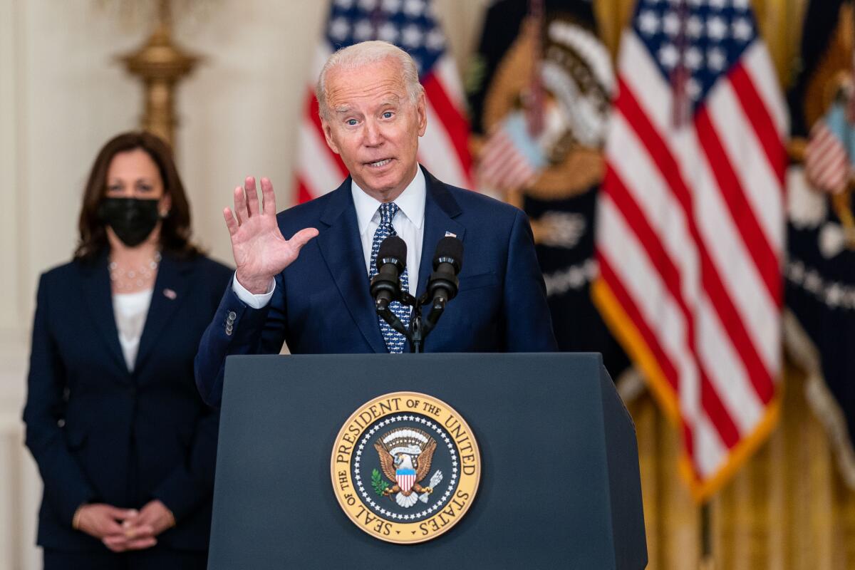 President Biden speaks at a lectern as Vice President Kamala Harris looks on