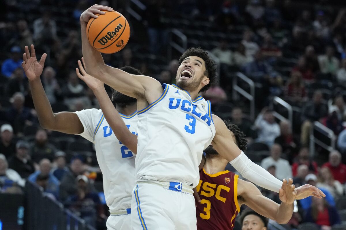 UCLA's Johnny Juzang (3) grabs a rebound in front of USC's Isaiah Mobley.