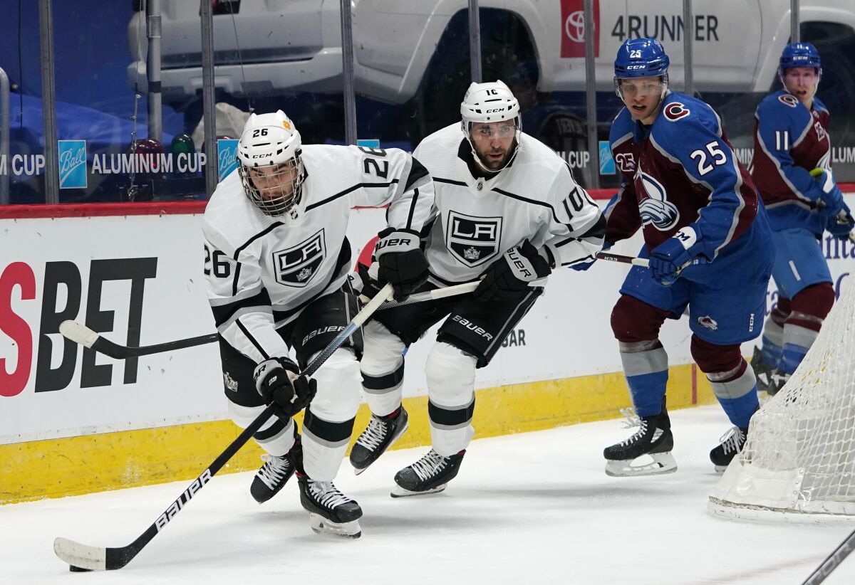 Kings defenseman Sean Walker controls the puck ahead of teammate Michael Amadio as Colorado forward Logan O'Connor.