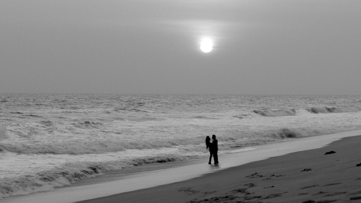 Two people embrace on a beach.