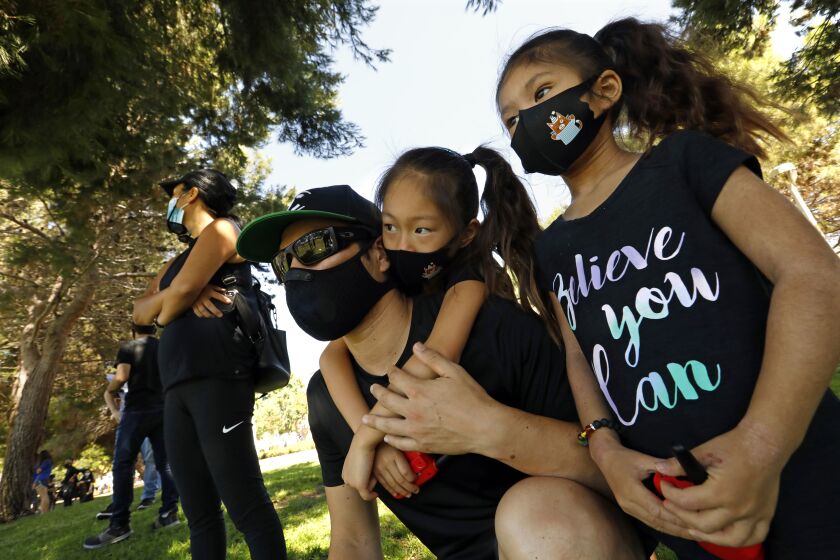 TORRANCE, CALIFORNIA-JULY 11, 2020-Zac Shannon, center, and his daughters, Teagan, 5, left, and Alina, right, and wife, Hitomi, far left, attend a rally against racism in Torrance on Saturday, July 11, 2020. A coalition of Asian-American civil and human rights organizations, community leaders and their supporters will hold a rally to demand justice for the victims of anti-Asian sentiment within the city and call on the City Council to recognize "the continued presence of racism within city limits and protect the public from future attacks from hate crimes." The demonstration will come one month after a woman's "racist verbal assault" rants in a Torrance park and toward people of Asian origin, which were captured on video, on June 10, according to contact. Victims of the alleged incidents will be present, contact says. (Carolyn Cole/Los Angeles Times)