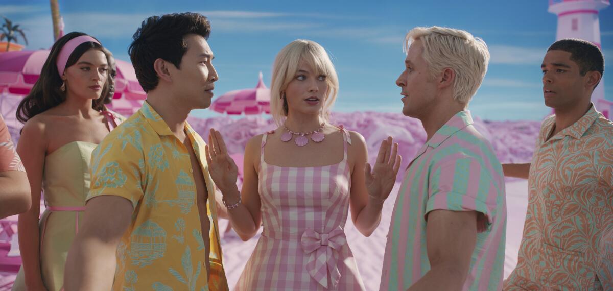 In a scene from 'Barbie,' Margot Robbie talks to Simu Liu and Ryan Gosling as other actors watch