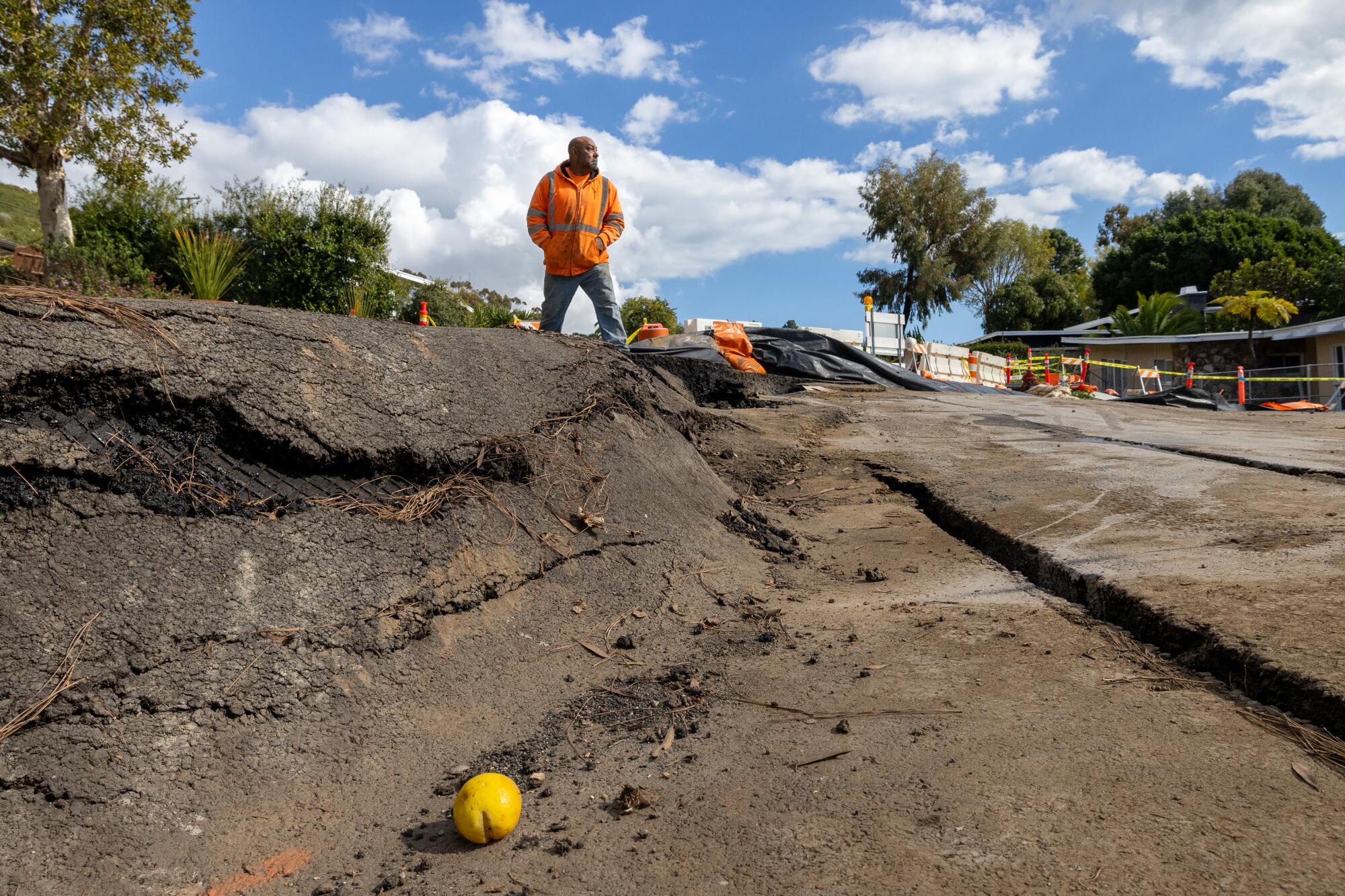 A construction worker walks along cracked pavement where land movement exacerbated by recent storms in Rancho Palos Verdes.