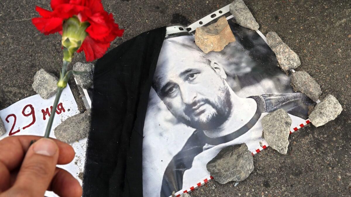 A mourner places a flower on a picture of Russian journalist Arkady Babchenko, who was reported killed on May 29, 2018, in Ukraine. He appeared at a Kiev news conference a day later, very much alive.