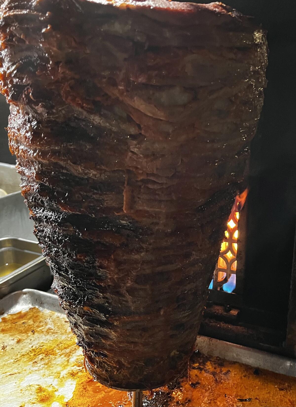 A flame keeps an al pastor spit warm and ready for tacos at an undisclosed and unpermitted taco stand in Anaheim.