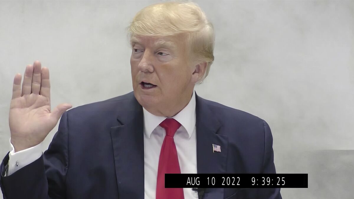 Donald Trump with his right hand raised in an image taken from video.