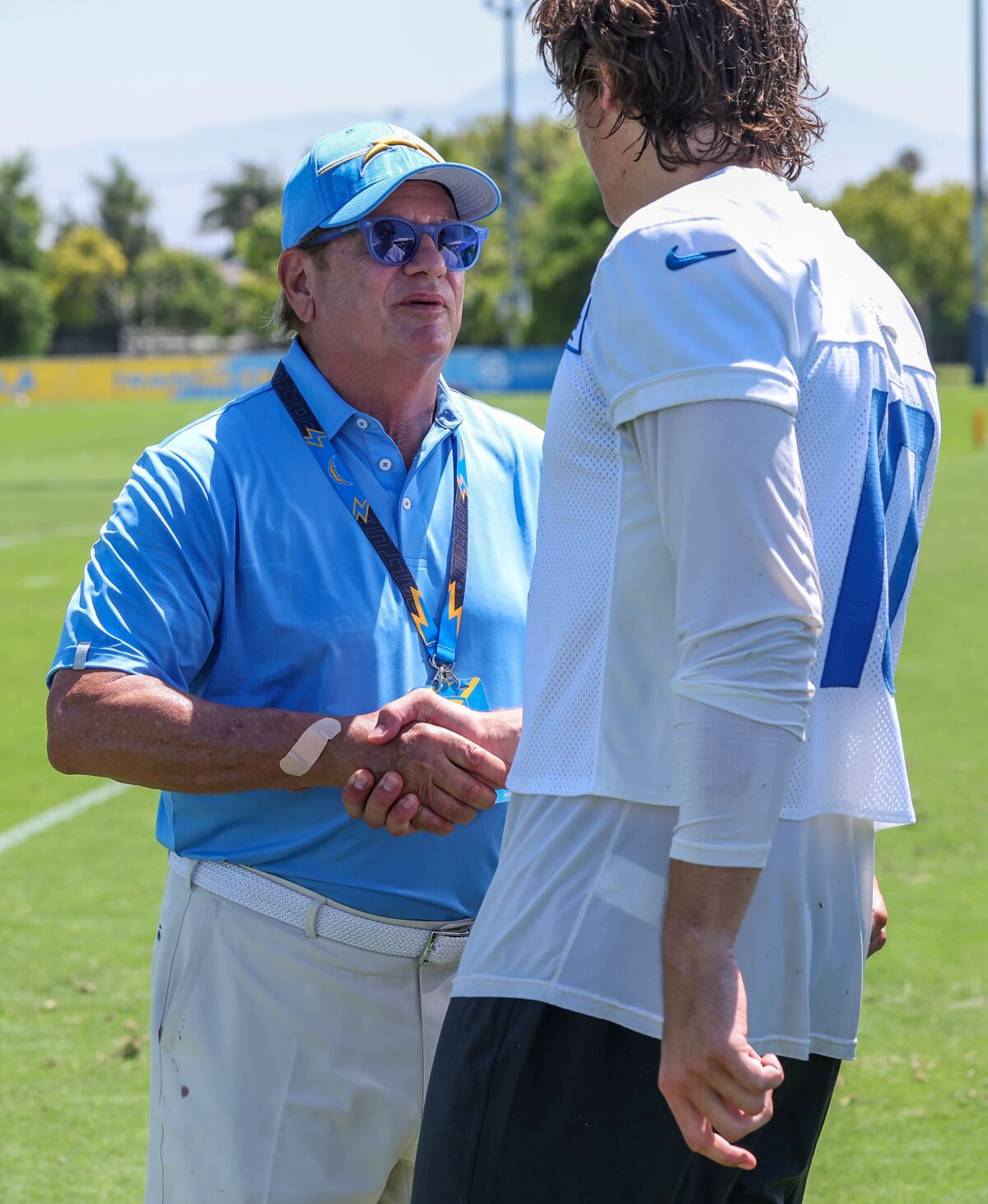 Chargers owner Dean Spanos greets quarterback Justin Herbert at training camp Wednesday.