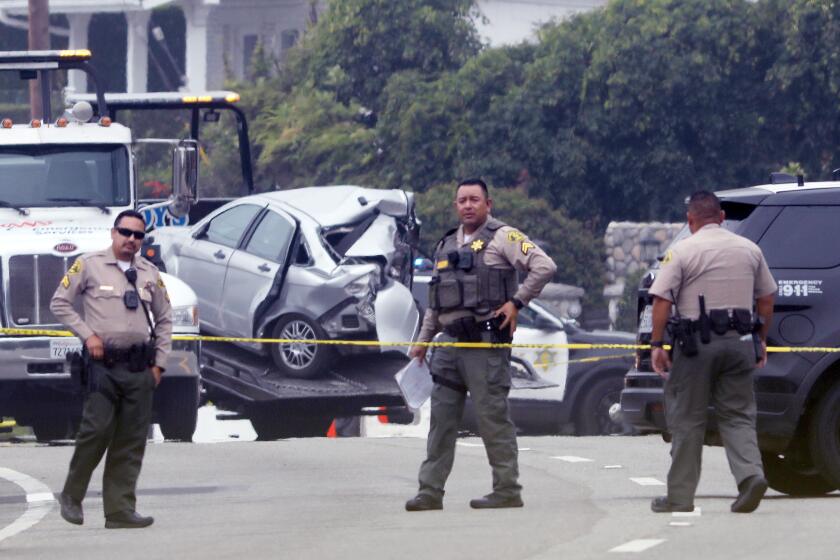 LOS ANGELES, CA - OCTOBER 18, 2023 - Sheriff deputies monitor the scene where four women were killed in a multi-vehicle crash in Malibu on October 18, 2023. A 22-year-old man was arrested after plowing into the pedestrians and parked cars. The crash was reported at 8:30 p.m. Tuesday in the 21600 block of Pacific Coast Highway where they found the victims of the crash, along with the severely damaged vehicles. The crash began when the suspect lost control of his BMW and slammed into multiple parked cars before ricocheting and fatally striking the women, who were standing on the side of the road. (Genaro Molina / Los Angeles Times)
