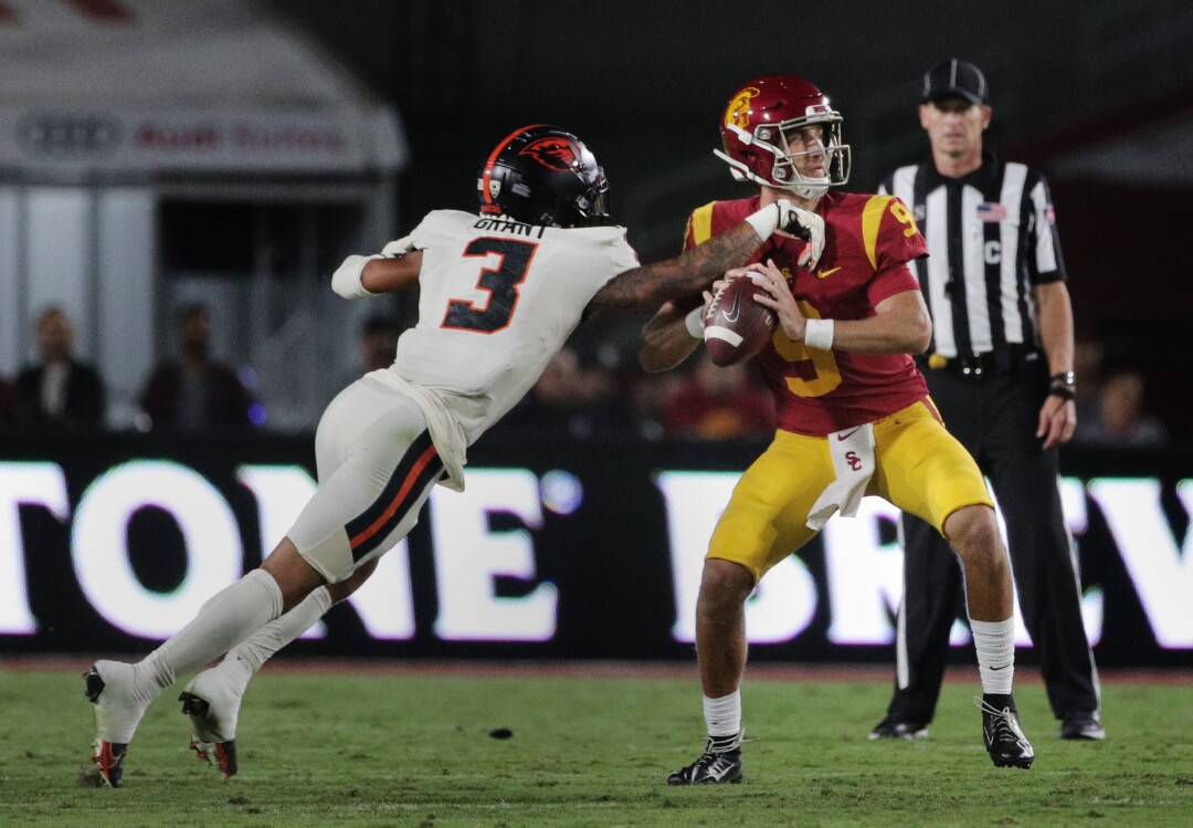 Oregon State defensive back Jaydon Grant, left, tries to slap the ball out of the hands of USC quarterback Kedon Slovis.