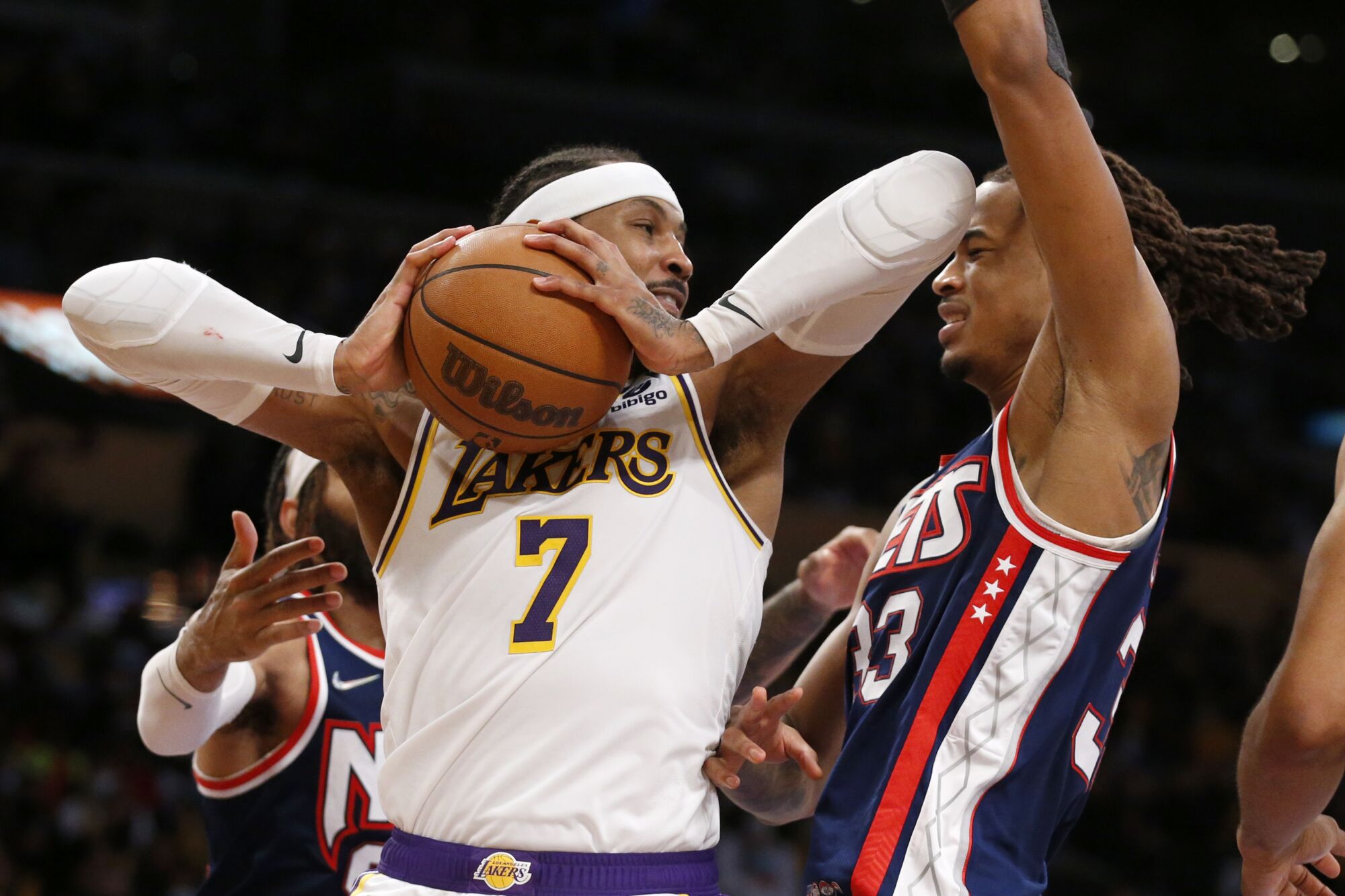Lakers forward Carmelo Anthony grabs a rebound while fending off Brooklyn's DeAndre' Bembry (95) and Nic Claxton (33).