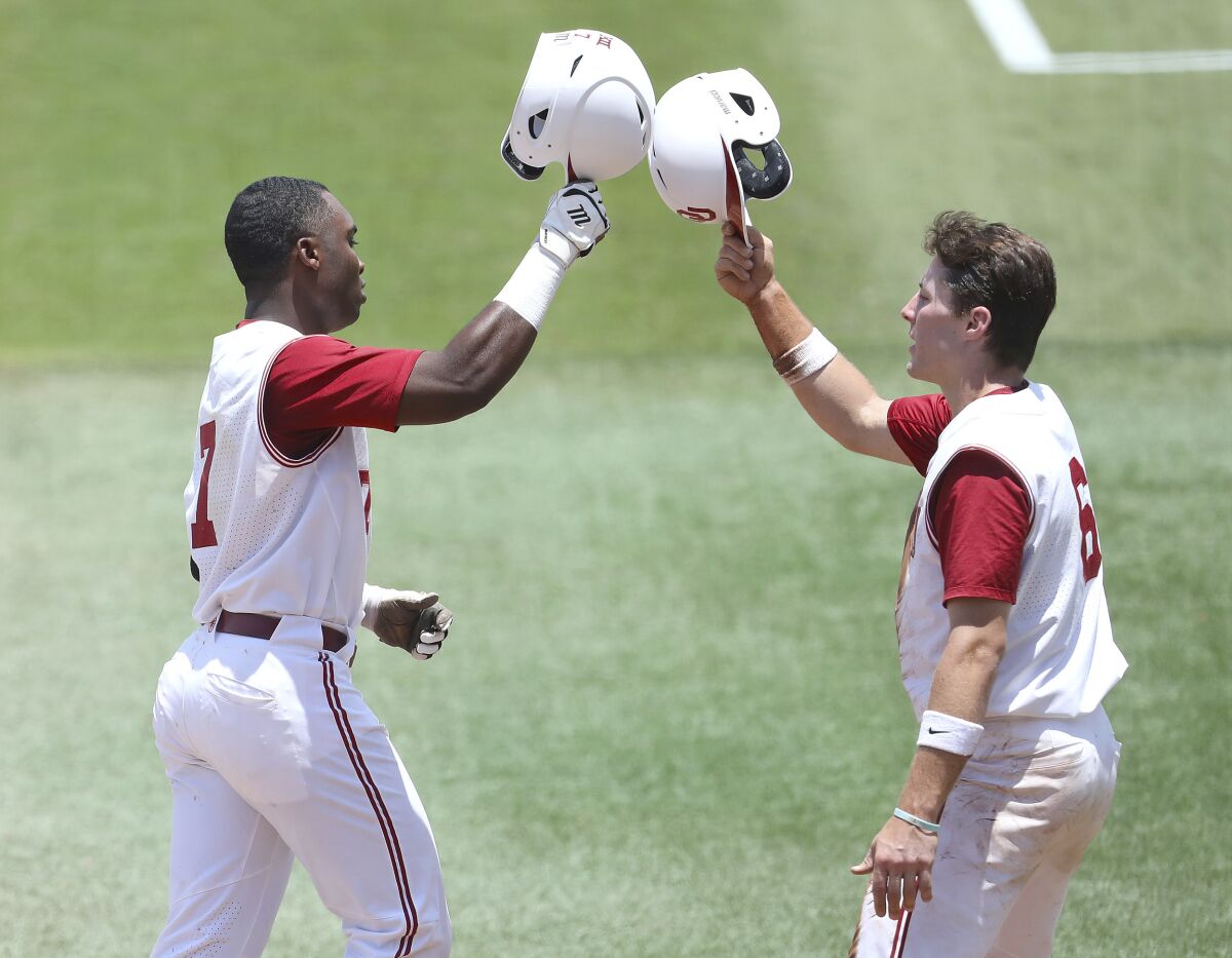 Oklahoma Kendall Pettis (7) and Wallace Clark (6) celebrate after Pettis hit a home run against Liberty during the first game of the Gainesville Regionals in the NCAA college Division 1 baseball championships in Gainesville, Fla., Friday, June 3, 2022. (Brad McClenny/The Gainesville Sun via AP)