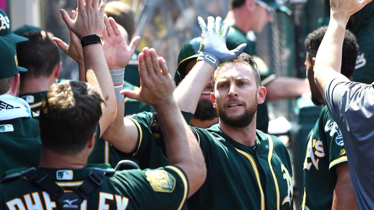 Oakland Athletics' Jed Lowrie is congratulated in the dugout after hitting a three-run home run in the fourth inning against the Angels at Angel Stadium on Sunday.