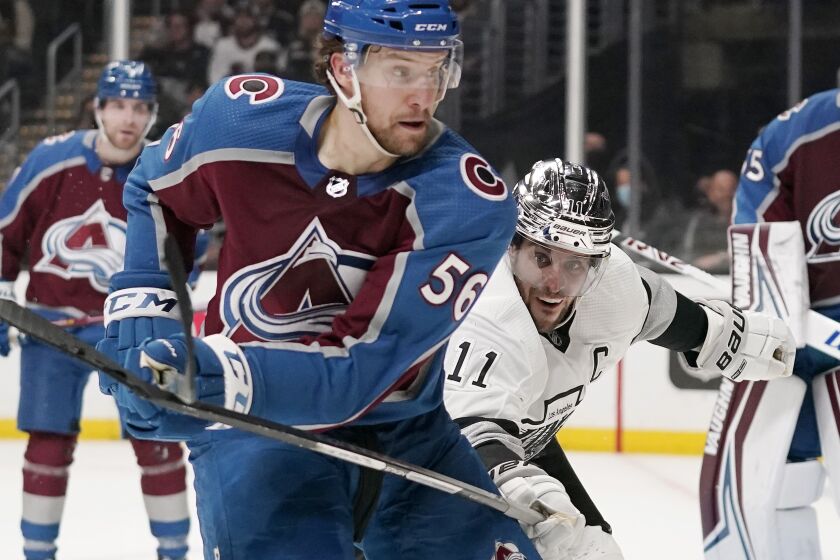 Los Angeles Kings center Anze Kopitar, right, reaches in on Colorado Avalanche defenseman Kurtis MacDermid during the second period of an NHL hockey game Thursday, Jan. 20, 2022, in Los Angeles. (AP Photo/Mark J. Terrill)