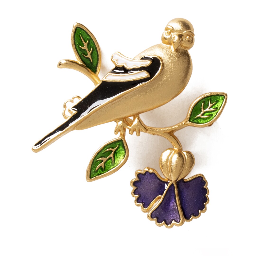 A brooch in the shape of a bird sitting on a branch.